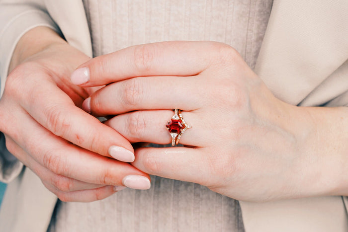 Hexagon Ruby Engagement Ring Set in 14K Solid Rose Gold by Aquamarise Gold, featuring a hexagon-cut ruby with diamond accents on a hand with natural-toned nails.