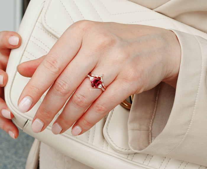 Hexagon Ruby Engagement Ring Set in 14K Solid Rose Gold by Aquamarise Gold, featuring a bold hexagon-cut ruby with diamond accents, styled on a hand with nude nails holding a cream leather bag.