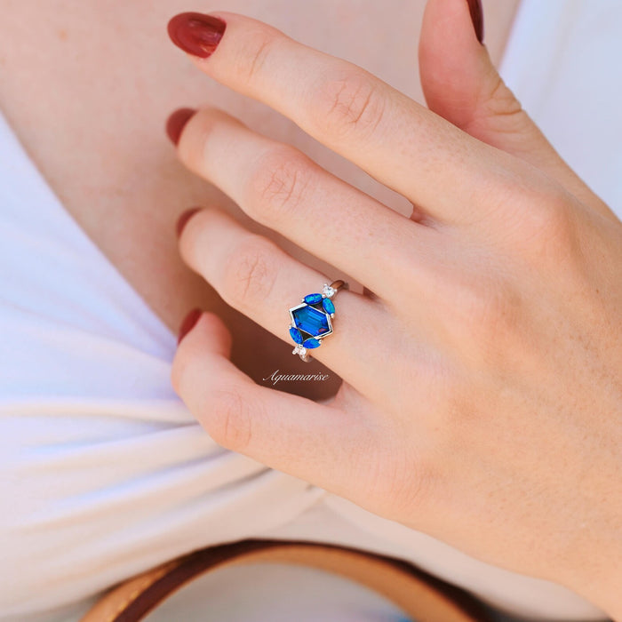 Blue Fire Opal & Sapphire Engagement Ring- Sterling Silver by Aquamarise, featuring a vivid blue opal and sapphire in a unique geometric sterling silver setting on a woman's hand.