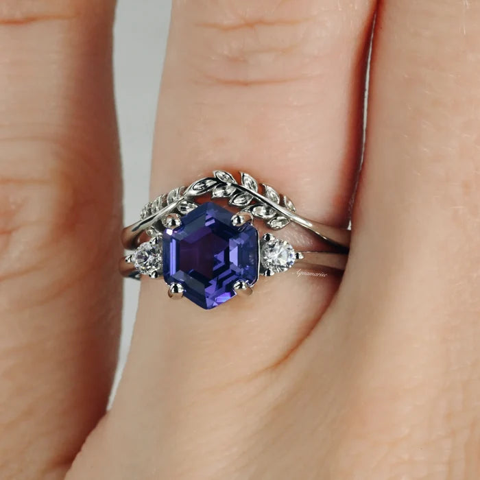 Hexagon Tanzanite Leaf Ring Set in Sterling Silver by Aquamarise featuring a hexagon-cut deep purple tanzanite center with leaf-inspired bands and sparkling side stones on a hand.