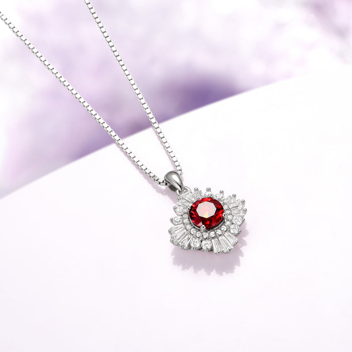 Joelle Natural Red Garnet Starburst Pendant Necklace in Sterling Silver by Aquamarise, featuring a vibrant red garnet surrounded by sparkling baguette and round accents in a starburst design.