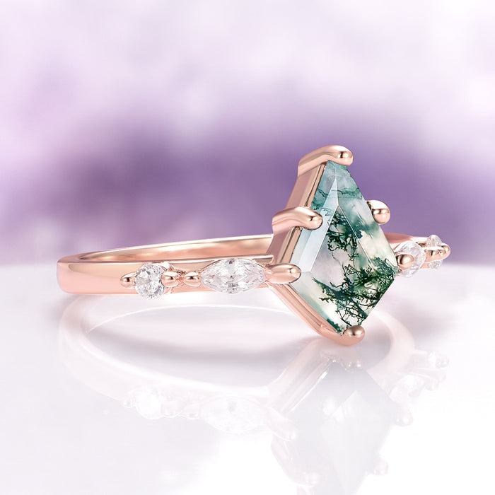Rose gold ring with a green gemstone on a white surface with a purple gradient background