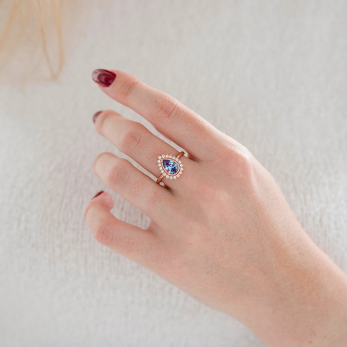 Lab Alexandrite Halo Engagement Ring in Solid 14K Rose Gold worn, featuring a pear-cut lab alexandrite and moissanite halo by Aquamarise Gold in a romantic rose gold setting.