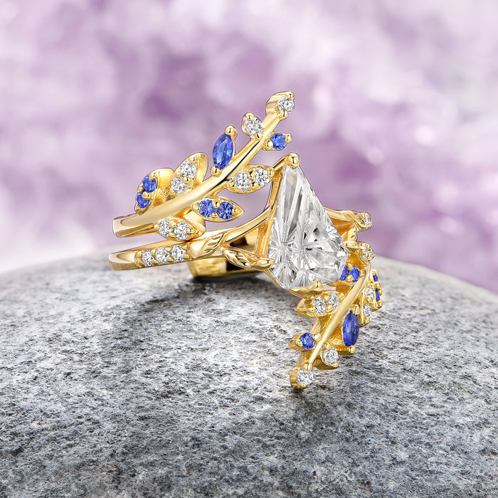 Fantasy Shield Cut Moissanite & Blue Sapphire Ring Set- 14K Solid Yellow Gold by Aquamarise Gold, featuring an intricate yellow gold band designed with leaf motifs accented by deep blue sapphires and sparkling moissanite, part of Solid Gold Engagement Rings and September Birthstone Jewelry collections.