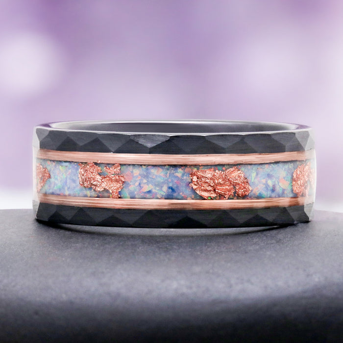Angled view of the 8mm Light Blue Fire Opal men's wedding band showing the hammered black tungsten facets and rose gold flecked opal inlay