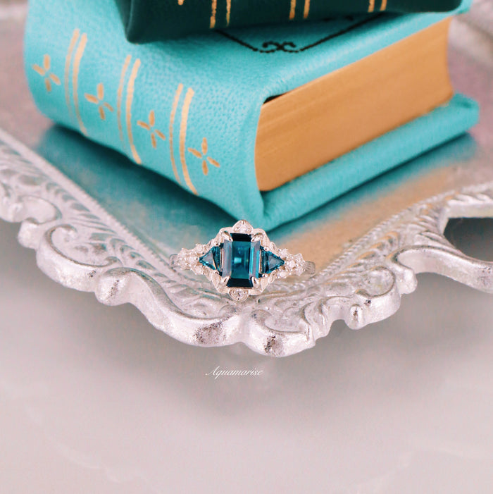 London Blue Topaz Leaf Engagement Ring in Sterling Silver by Aquamarise featuring a deep blue emerald-cut topaz with triangular side stones in an Art Deco-inspired design.