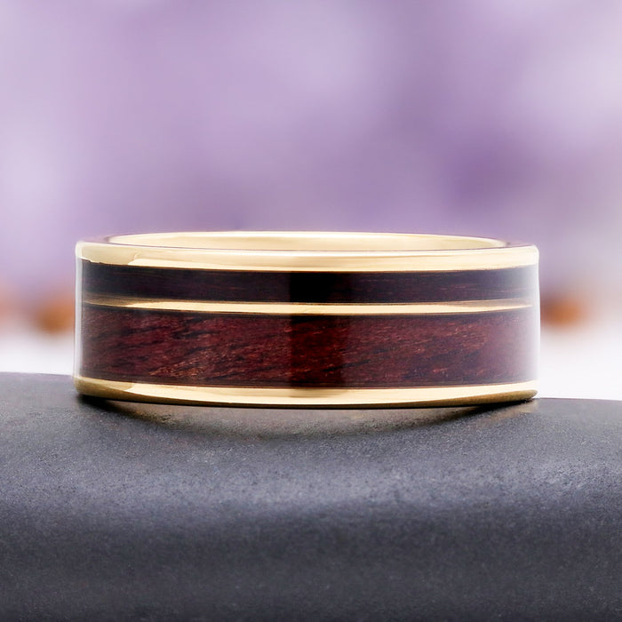 8mm M1 Garand and purpleheart wood wedding band in gold tungsten carbide resting on a dark stone