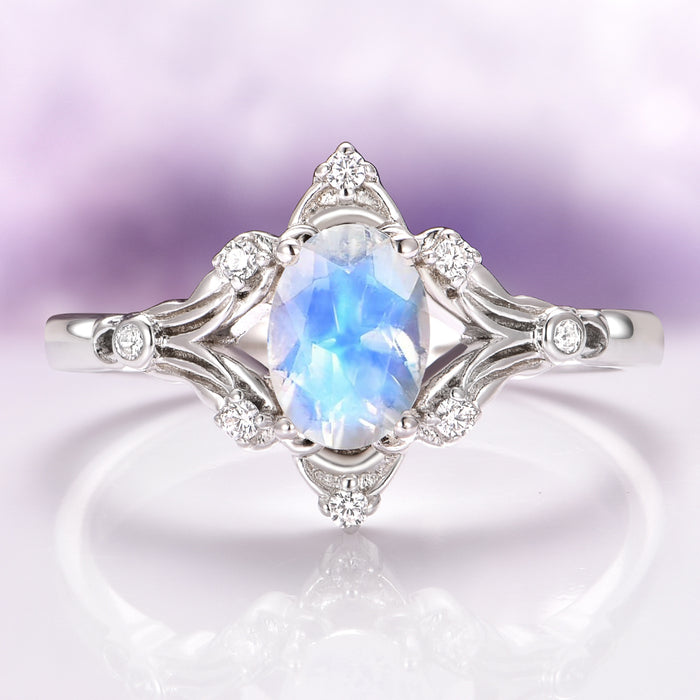 Maeve Vintage Moonstone Engagement Ring in 14K White Gold featuring an oval moonstone with ethereal blue flashes, surrounded by delicate white gold filigree and small sparkling diamond accents, crafted by Aquamarise Gold.