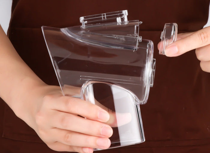 A person holding a mandoline vegetable slicer, showcasing its detachable parts for convenient food preparation.