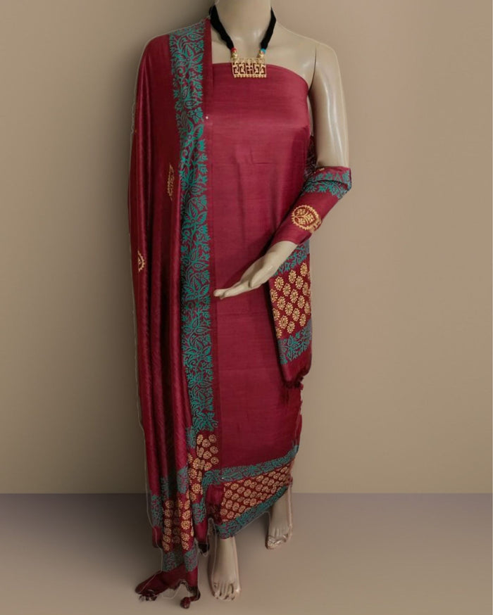 Maroon katan silk unstitched suit set with hand block printed teal borders on both long edges of the dupatta, in floral and circular geometric motifs with gold and cream accents.