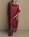 Maroon katan silk unstitched suit set with hand block printed teal borders on both long edges of the dupatta, in floral and circular geometric motifs with gold and cream accents.