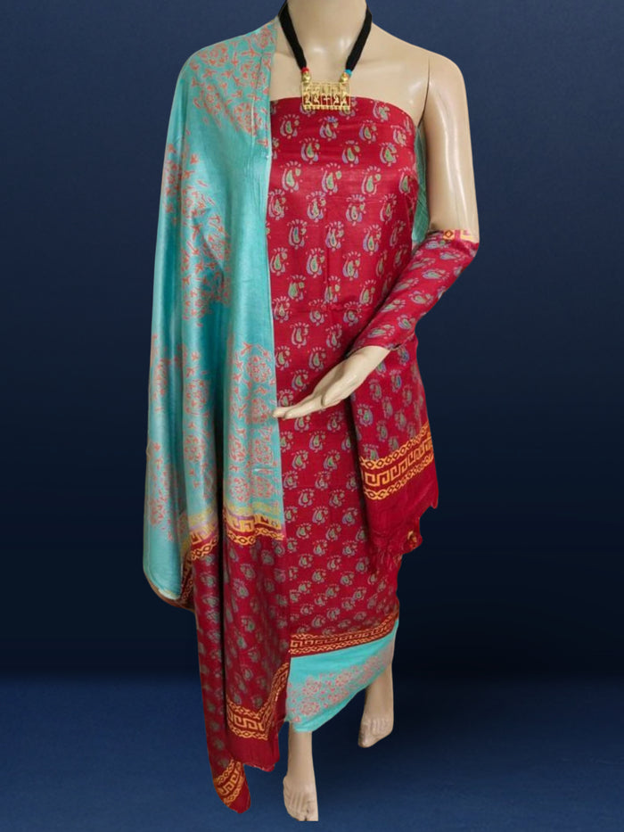 Maroon katan silk unstitched suit set hand block printed with small turquoise botanical motifs and angular geometric key-pattern bands at the ends.