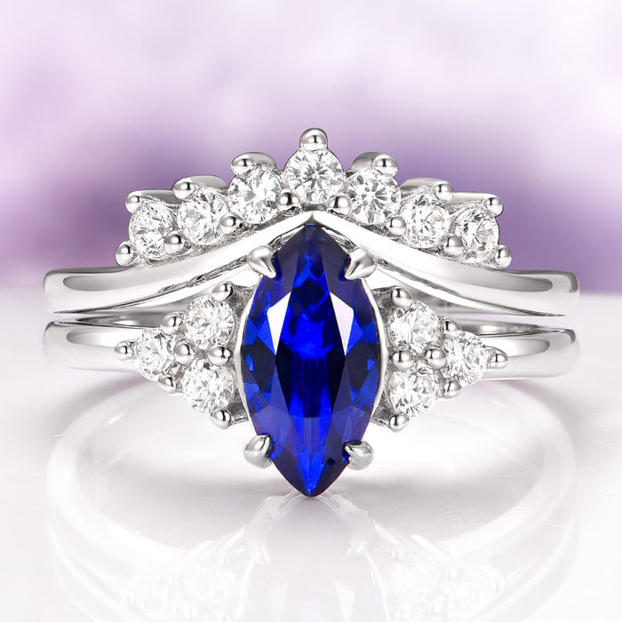Marquise Cut Blue Sapphire Bridal Ring Set in Sterling Silver by Aquamarise featuring a deep blue marquise sapphire surrounded by sparkling round accents on a sterling silver band.