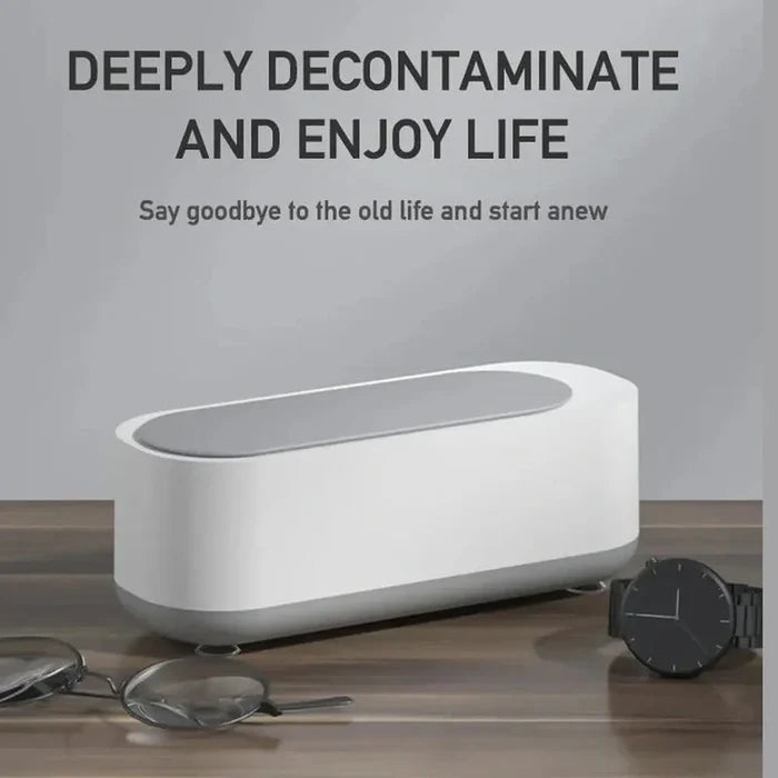 Mini Ultrasonic Jewelry Cleaner on a wooden surface with glasses and a watch nearby