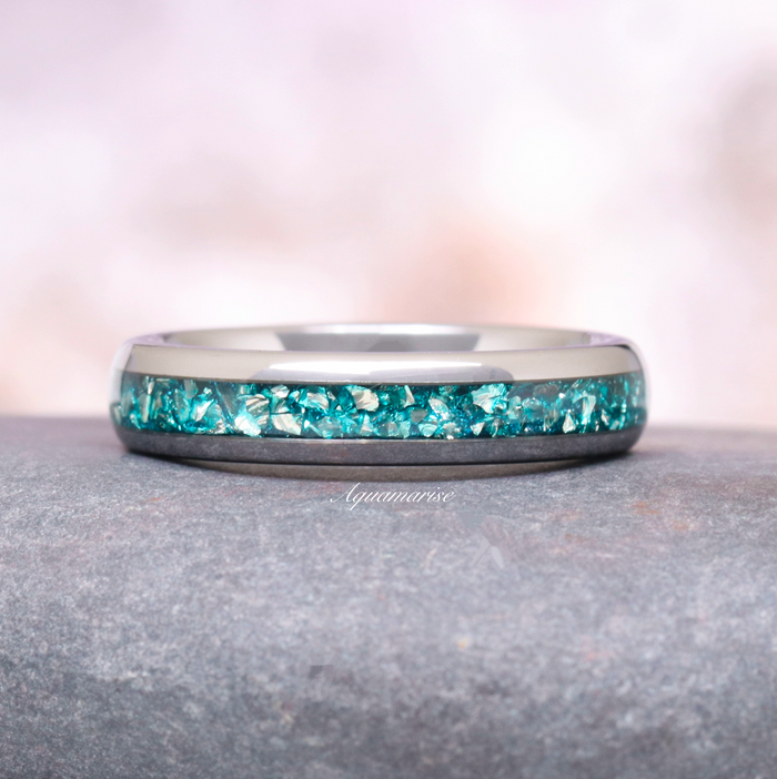 Minimalist Crushed Aquamarine Couples Ring Set by Aquamarise featuring a polished silver band with vibrant crushed aquamarine inlay, showcased on a smooth stone surface.
