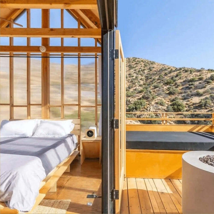 Minimalist silent alarm clock on a bedside table in a wooden cabin bedroom with a view.