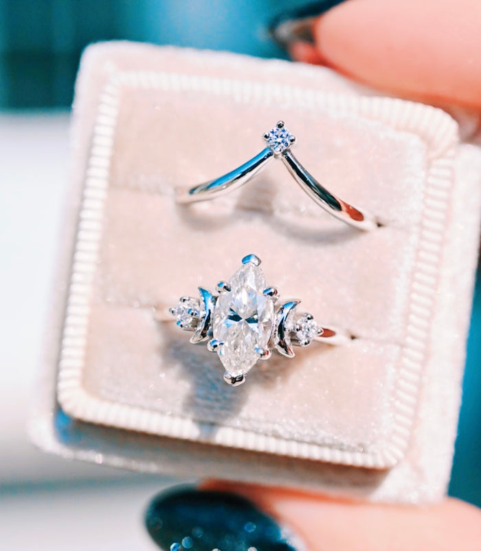 Moissanite & Crescent Moon Constellation Couples Ring Set featuring a marquise-cut moissanite center flanked by crescent moon and round accents in polished sterling silver by Aquamarise, showcased in a blush velvet ring box.