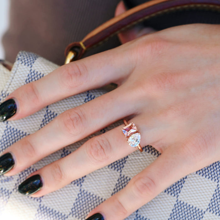 Toi Et Moi Morganite and Simulated Diamond Ring in Sterling Silver by Aquamarise featuring a rose gold band with an emerald-cut morganite and pear-shaped simulated diamond on a hand holding a patterned bag