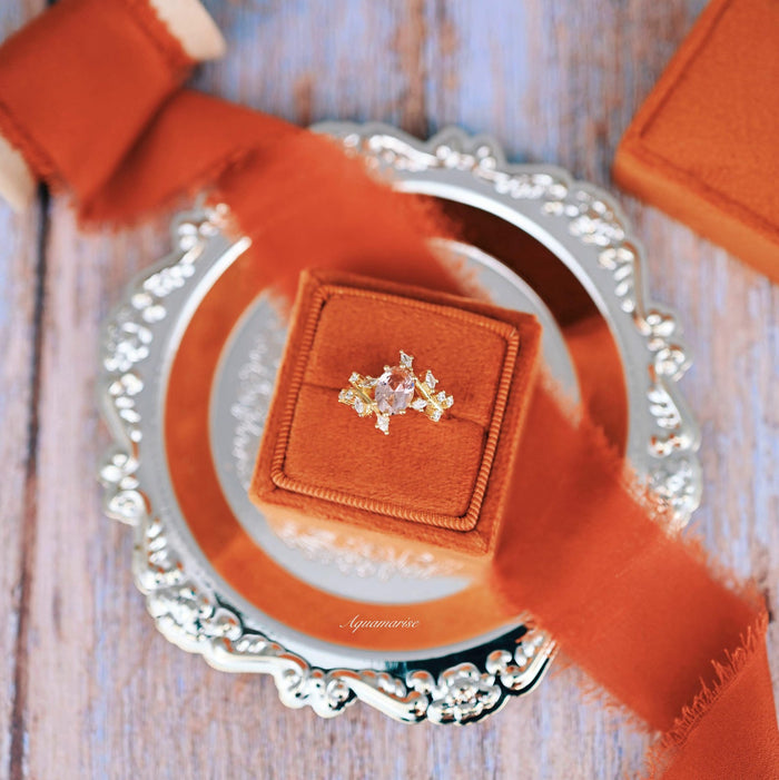 Pink Lab-Grown Diamond Fairy Leaf Engagement Ring in 14K Solid Yellow Gold (IGI Certified) displayed on a burnt orange velvet ring box atop a decorative silver tray, styled with a matching sheer orange ribbon by Aquamarise Gold.