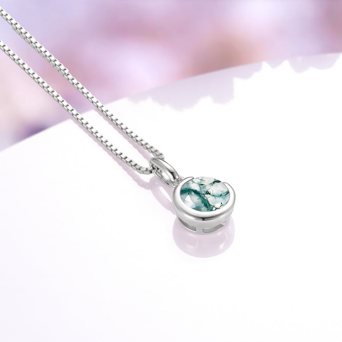Moss Agate Crescent Moon Necklace in Sterling Silver by Aquamarise, featuring a polished round moss agate gemstone embraced by a smooth crescent moon pendant on a delicate sterling silver chain, part of Moss Agate Jewelry and Meaningful Jewelry Gifts collections.