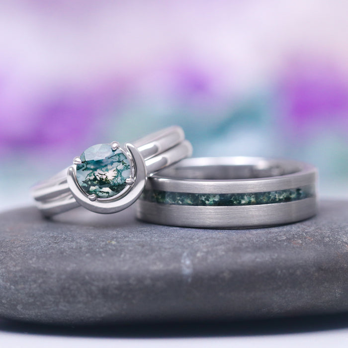 Green Moss Agate & Crescent Moon Couples Ring Set featuring a round moss agate stone cradled by a crescent moon-shaped sterling silver band alongside a matte silver band with an inlay of green moss agate, crafted by Aquamarise from Matching Couples' Rings and Moss Agate Jewelry collections.