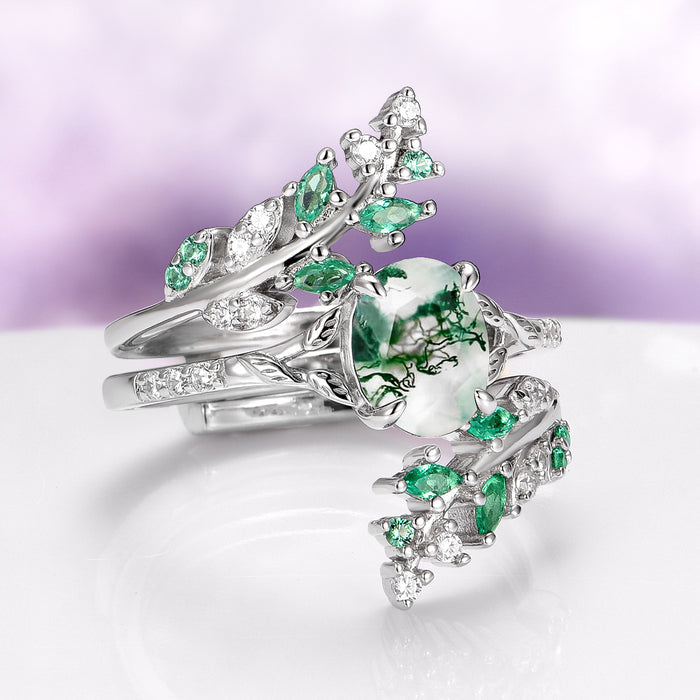 Moss Agate & Emerald Fairy Leaf Couples Ring Set by Aquamarise featuring a nature-inspired design with a central moss agate stone surrounded by marquise emerald accents and intricate silver leaf motifs, part of Matching Couples' Rings and May Birthstone Jewelry collections.