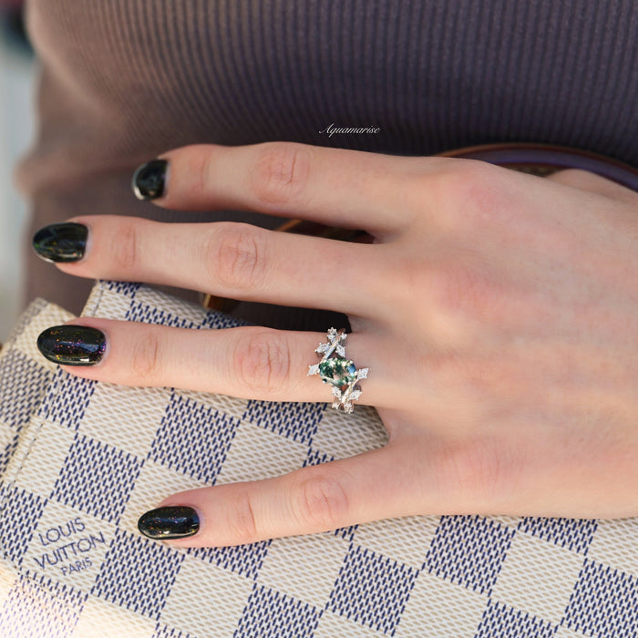 Moss Agate Leaf Couples Ring Set by Aquamarise featuring sterling silver band with green moss agate stone and leaf motifs, worn on a hand with black nail polish holding a patterned clutch.