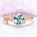 Rose gold ring with a green gemstone on a light purple background