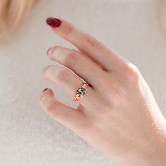 Moss Agate Leaf Ring in 14K Rose Gold Vermeil by Aquamarise, featuring a 7mm round natural green moss agate stone with an elegant leaf-inspired band on a hand with burgundy nails.