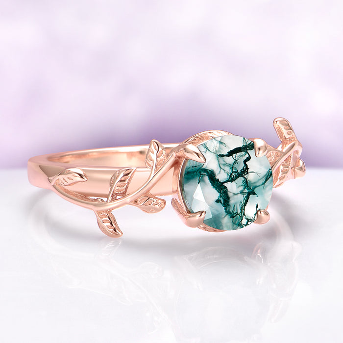 Rose gold ring with a green gemstone on a white background