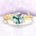 Gold ring with a green gemstone on a white and purple gradient background