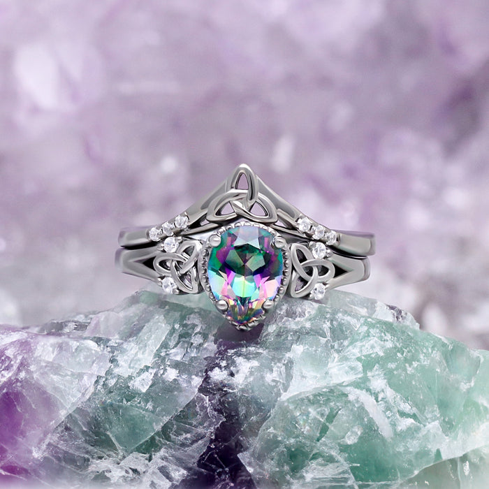 Celtic Knot Mystic Topaz Ring Set in Black by Aquamarise, styled on green and purple crystals to show the Celtic knot bands.