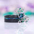 Mystic Topaz & Galaxy Opal Leaf Couples Ring Set featuring a silver nature-inspired ring with multicolor topaz and green stones and a black band with a galaxy opal inlay by Aquamarise.