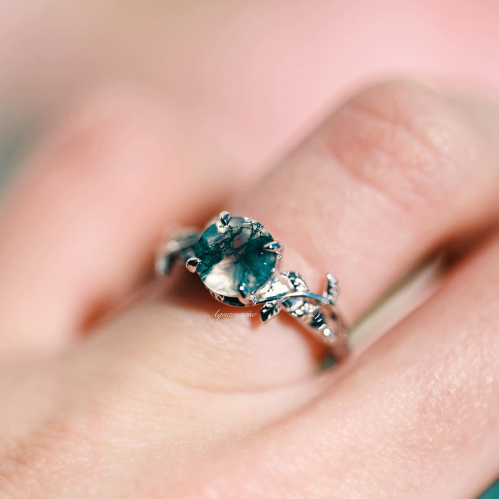 Natural Green Moss Agate Leaf Ring in Sterling Silver by Aquamarise featuring a round moss agate stone with green inclusions and a detailed leaf pattern on the silver band.
