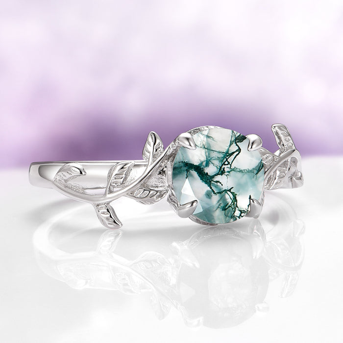 Natural Green Moss Agate Leaf Ring in Sterling Silver by Aquamarise with a round moss agate stone featuring green veins and an intricate leaf-inspired silver band design.