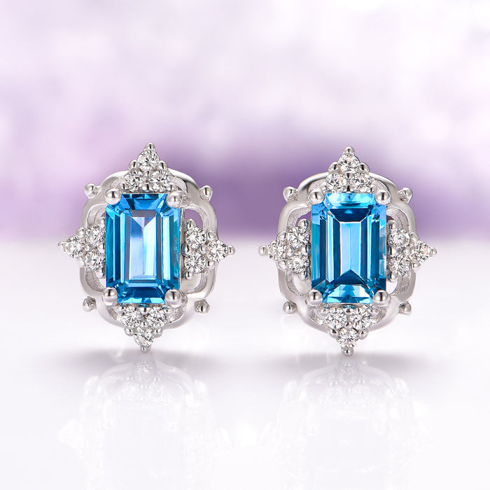 Natural London Blue Topaz Earrings in Sterling Silver by Aquamarise, featuring emerald-cut blue topaz stones surrounded by sparkling diamond accents in a vintage-inspired setting.