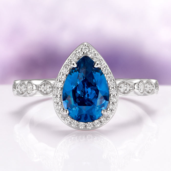 Natural London Blue Topaz Engagement Ring in 14K White Gold by Aquamarise Gold, featuring a pear-shaped deep blue topaz center framed by a sparkling diamond halo on a detailed white gold band, part of Solid Gold Engagement Rings and November Birthstone collections.