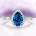 Natural London Blue Topaz Engagement Ring in 14K White Gold by Aquamarise Gold, featuring a pear-shaped deep blue topaz center framed by a sparkling diamond halo on a detailed white gold band, part of Solid Gold Engagement Rings and November Birthstone collections.