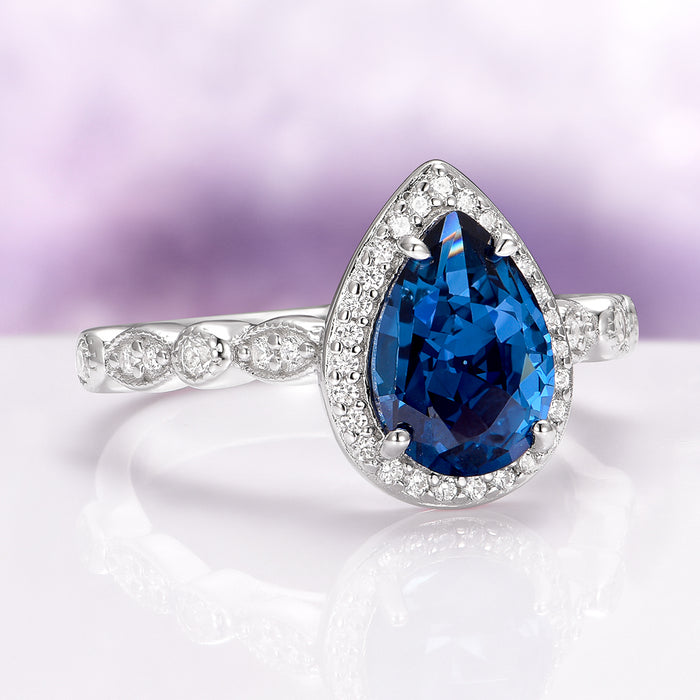 Natural London Blue Topaz Engagement Ring in 14K White Gold showcasing a pear-shaped deep blue topaz surrounded by a halo of diamonds on a delicate band, crafted by Aquamarise Gold and featured in Solid Gold Engagement Rings and November Birthstone collections.
