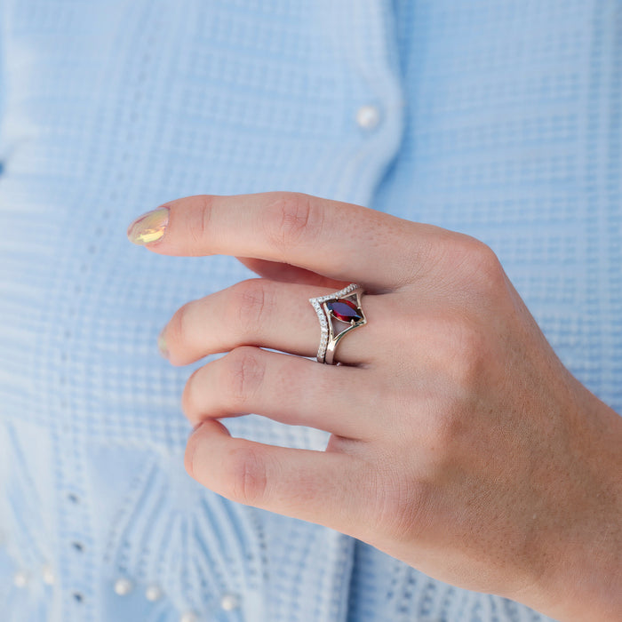 Natural Red Garnet Marquise Cut Engagement Ring Set in 14K White Gold showcased on a hand with a light blue textured blouse, featuring a marquise-shaped deep red garnet surrounded by delicate white gold and diamond accents, crafted by Aquamarise Gold.