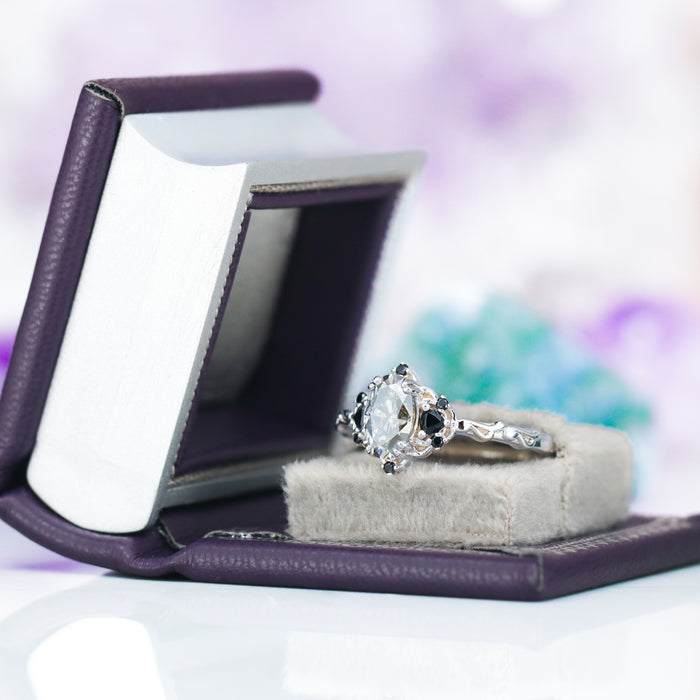 Night Court Handmade Leather Book Ring Box (Small) by Aquamarise with a silver unique engagement ring, displayed on a grey cushion inside a purple leather book-style ring box.
