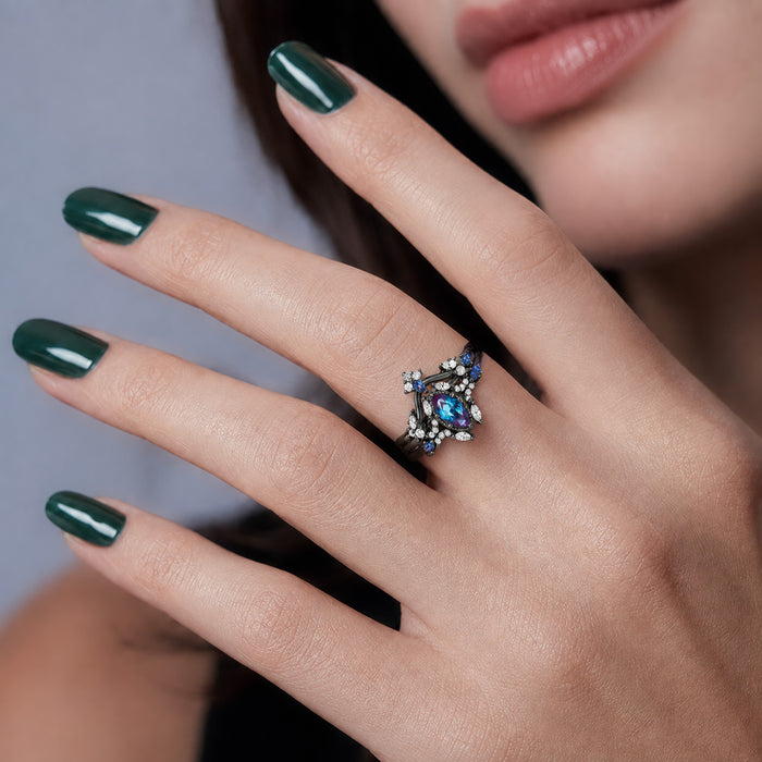 Nightbriar Lab-Grown Alexandrite Bridal Ring Set in Black Ruthenium by Aquamarise, worn on the hand of a model with dark green nails.