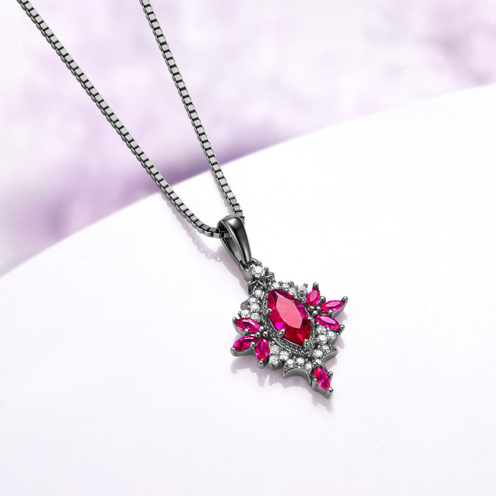 Angled view of the Nightbriar ruby pendant showing the red marquise rays radiating from the milgrain frame and the tapered bail on the box chain