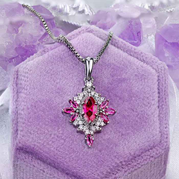 Nightbriar lab-grown ruby pendant necklace on a lilac velvet ring box, red marquise rays around the milgrain frame