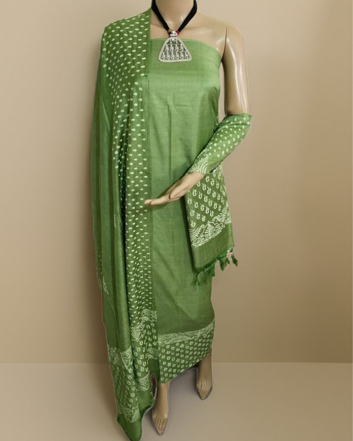 Olive green Katan silk suit set hand block printed all over with small white geometric shapes and dot clusters, with a wide dense geometric band on the dupatta and sleeve ends.