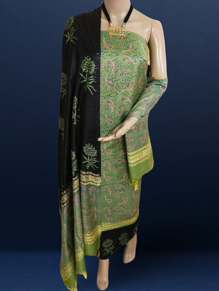 Olive green Katan silk unstitched suit set with small red and black paisley motifs, mustard yellow accents and a wide geometric printed border at the hem