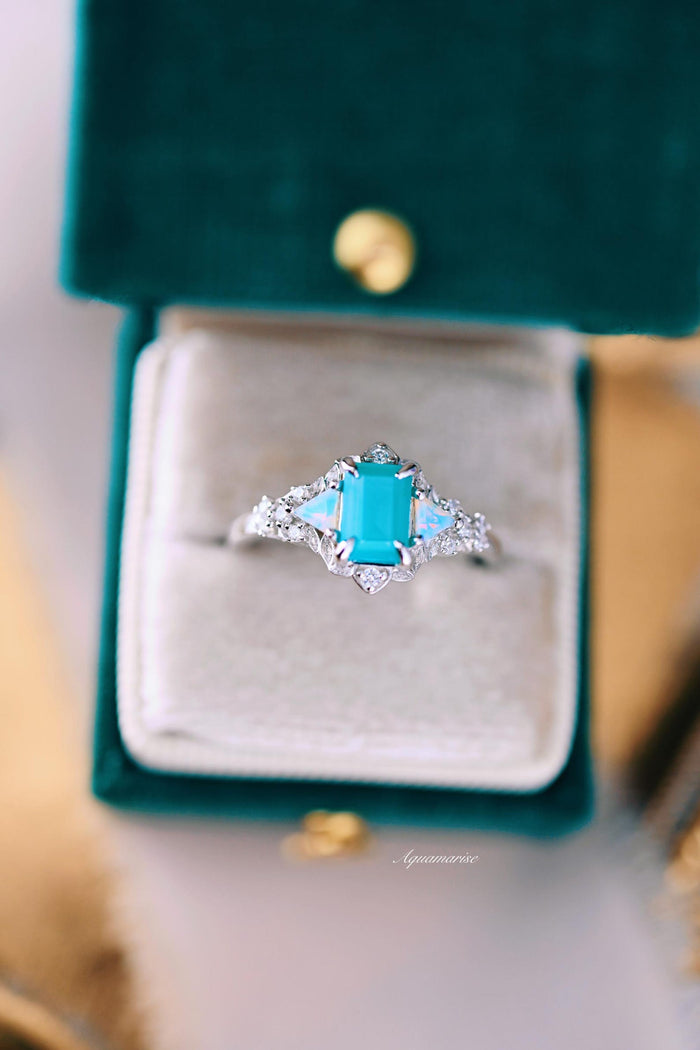 Opalescent Blue Sapphire Mermaid Engagement Ring in Sterling Silver by Aquamarise, featuring a radiant rectangular blue sapphire surrounded by delicate diamond accents on an intricate sterling silver band, showcased in a velvet ring box.