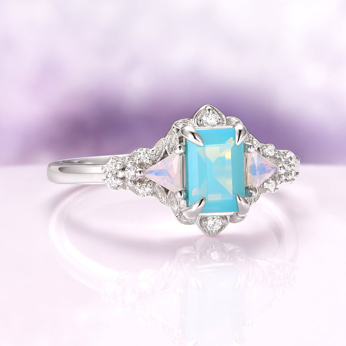 Opalescent Blue Sapphire Mermaid Engagement Ring in Sterling Silver by Aquamarise, featuring a radiant emerald-cut blue sapphire flanked by triangular opal accents and surrounded by sparkling diamonds on an intricate sterling silver band, part of Sterling Silver Rings, September Birthstone Jewelry, and Nature-Inspired Engagement Rings collections.