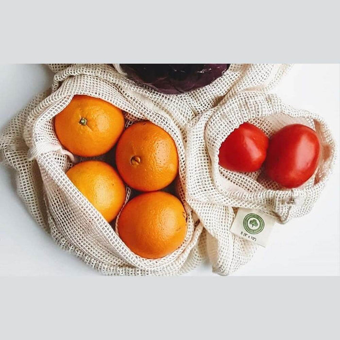Organic cotton reusable produce bags holding oranges and tomatoes, perfect for eco-friendly shopping.