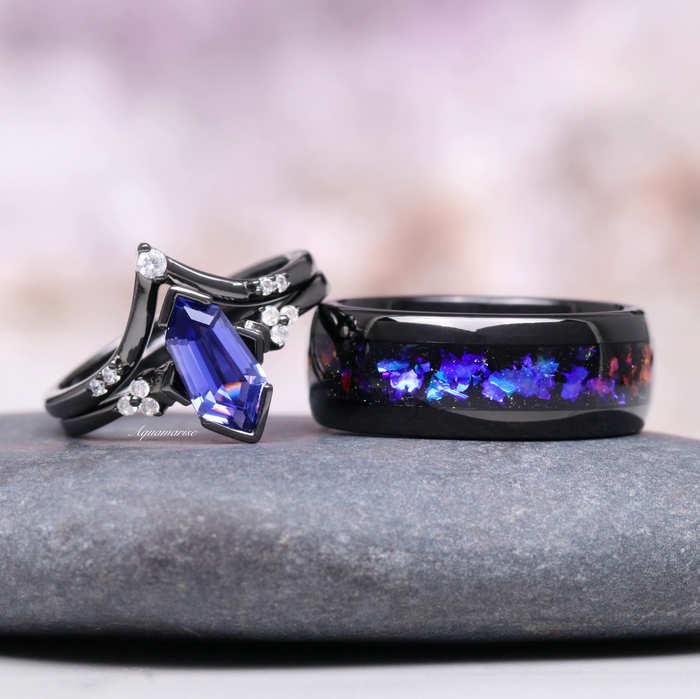 Orion Nebula™ & Tanzanite Couples Ring Set by Aquamarise featuring a black band with vibrant blue tanzanite and diamond accents beside a matching black band with cosmic nebula inlay.